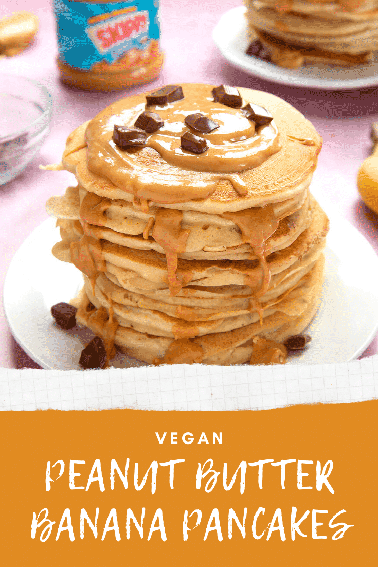 A stack of vegan peanut butter banana pancakes on a white plate. The stack is drizzled with more peanut butter and scattered with chunks of vegan chocolate. The caption reads: vegan peanut butter banana pancakes.