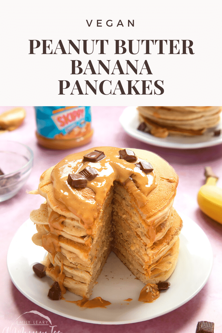 A stack of vegan peanut butter banana pancakes on a white plate. The stack is drizzled with more peanut butter and scattered with chunks of vegan chocolate. A wedge of pancakes is cut from the whole stack. The caption reads: vegan peanut butter banana pancakes.