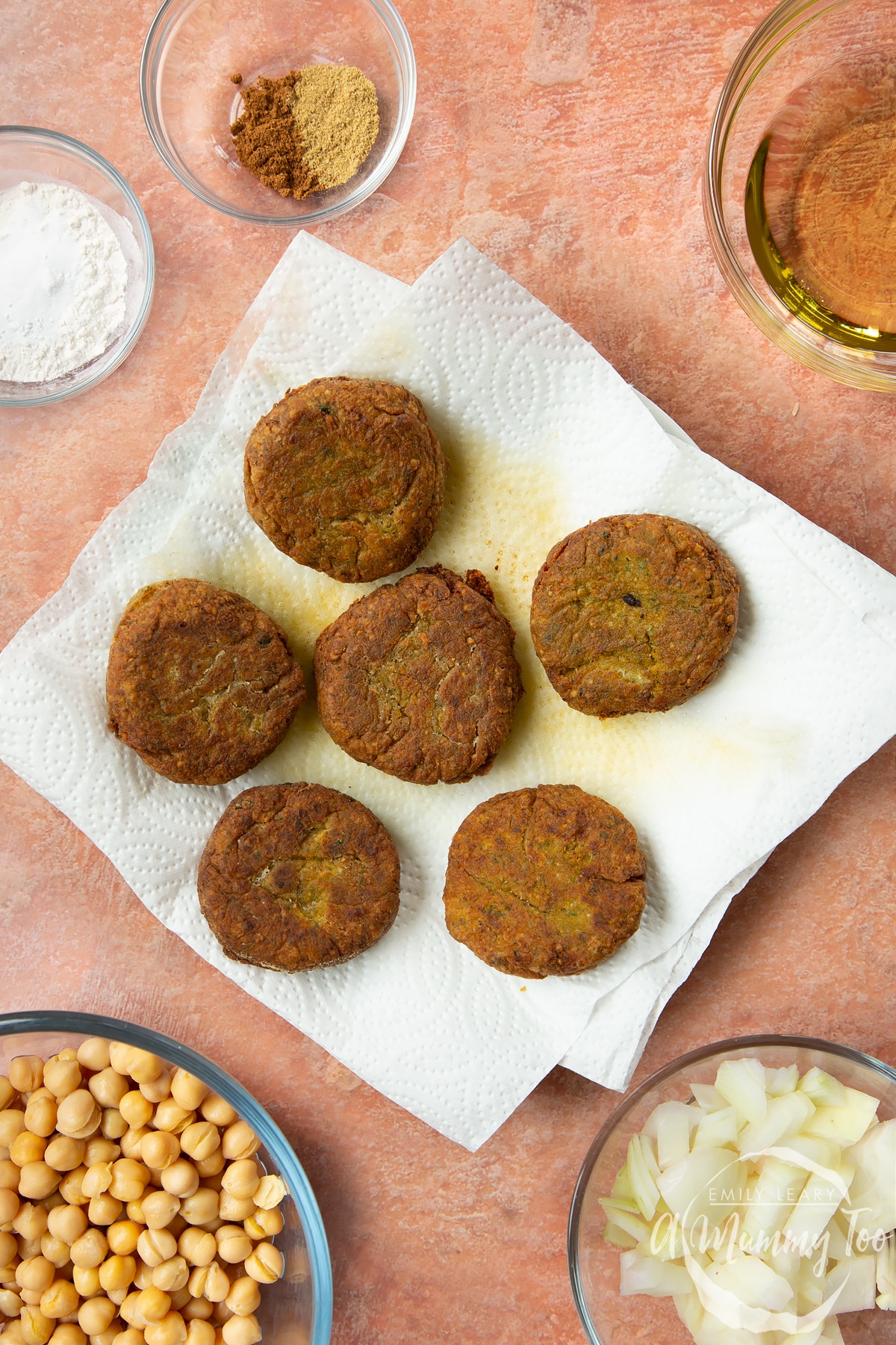 Five freshly fried harissa falafel draining on kitchen paper.