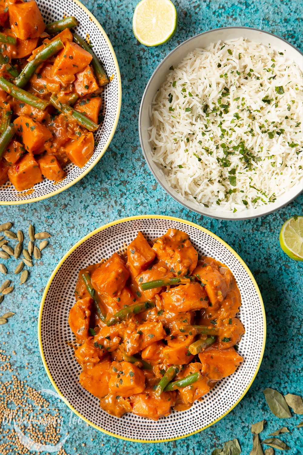 Vegan Sri Lankan curry in two yellow and black bowls, shown from above. Ingredients are scattered around it.