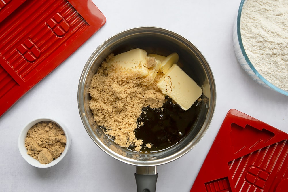 A saucepan, surrounded by equipment to make a gingerbread house. In the pan is butter, sugar, black treacle and golden syrup.