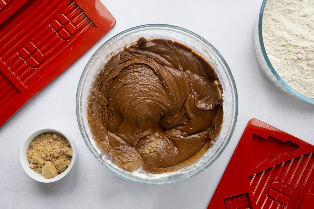 A bowl, surrounded by equipment to make a gingerbread house. In the bowl is a soft gingerbread dough.