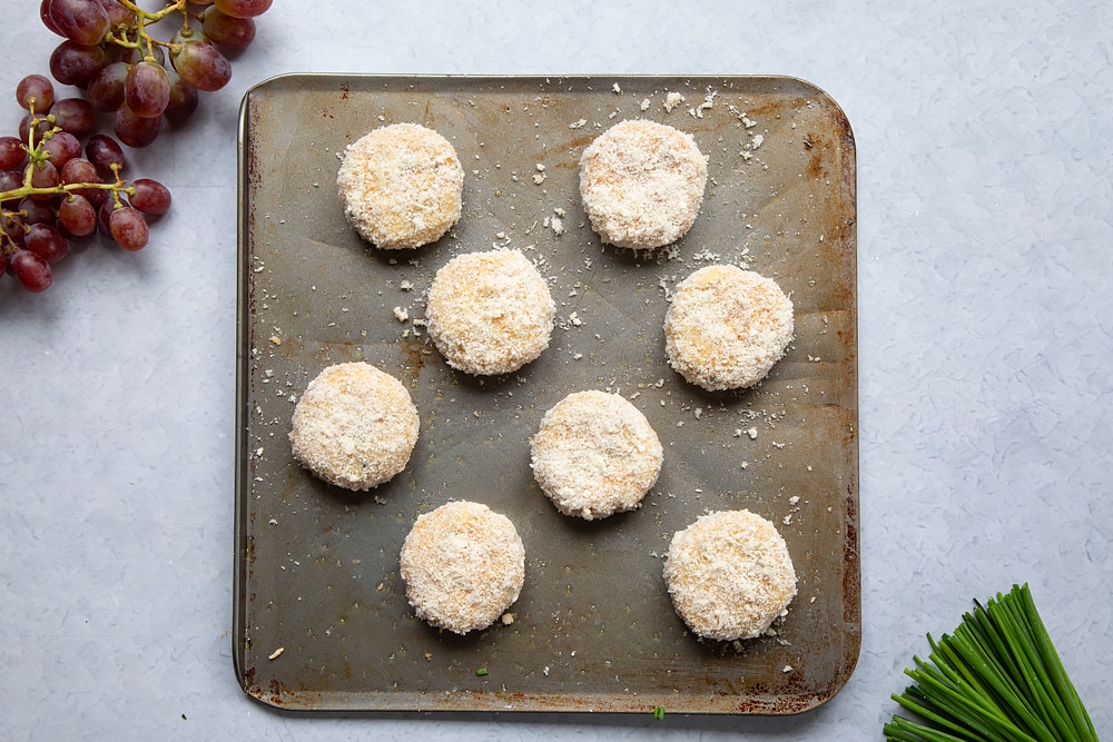 A baking tray with 8 fishcakes ready to be baked in the oven. 