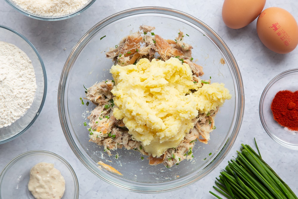 Adding cold mashed potato to the bowl of horseradish, chives, salt,  pepper and mackerel.